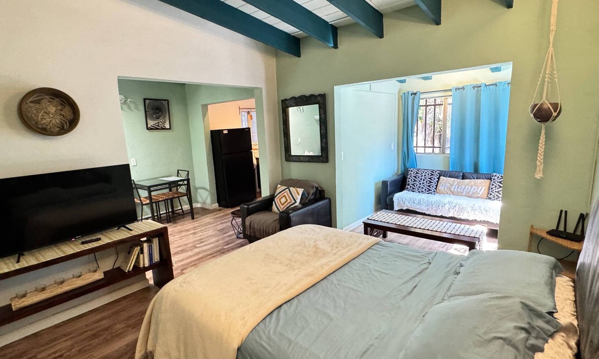 San Antonio del Mar Apartment | A bright, colorful escape just 3 blocks from the ocean in San Antonio del Mar. Sage-green walls and breezy teal curtains set a laid-back coastal mood, with a comfy queen bed, sofa bed, and full kitchen. Shared laundry available in the garage area.